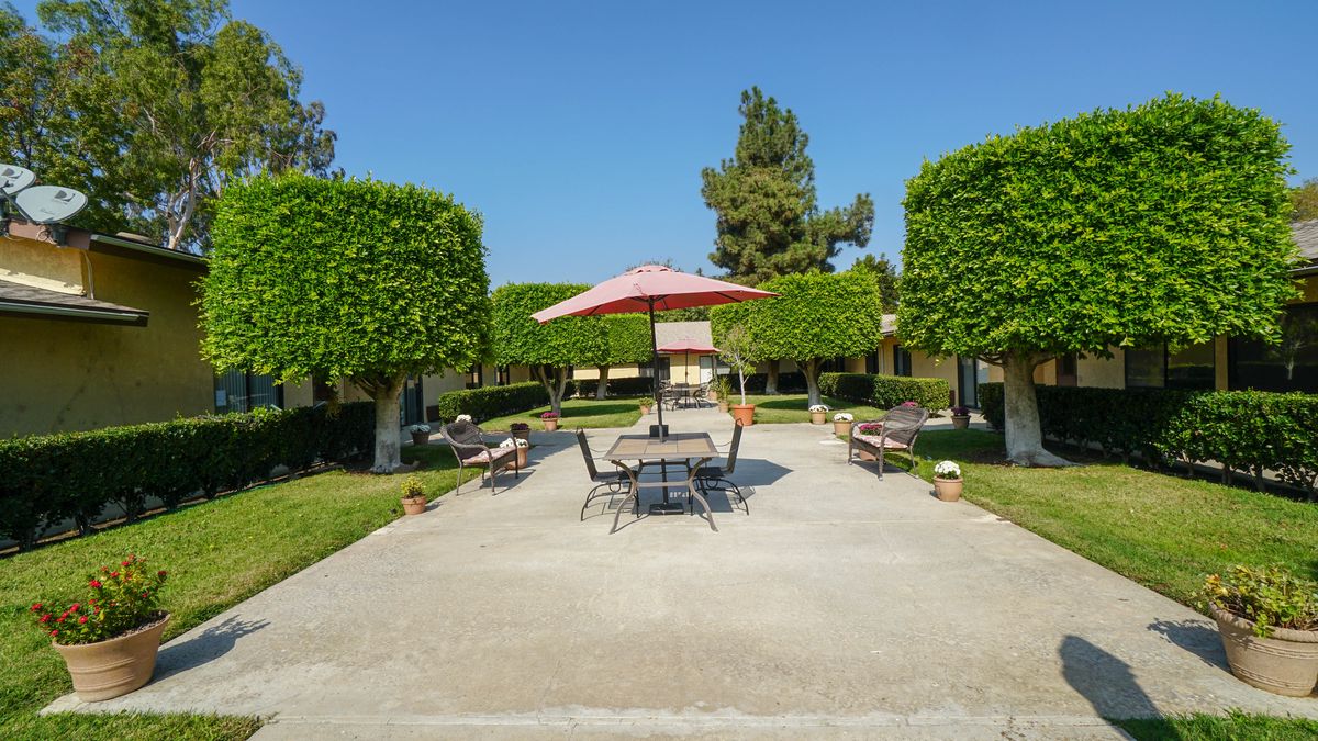 Senior enjoying summer at Santa Anita Assisted Living community with lush gardens and modern villas.