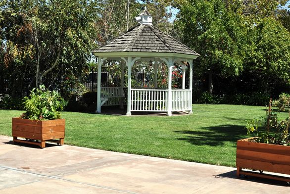 Outdoor view of Villa Sorrento senior living community with gazebo, potted plants and architecture.