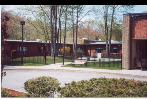 Senior living community, The Friendly Home in Woonsocket, featuring lush greenery and cityscape.
