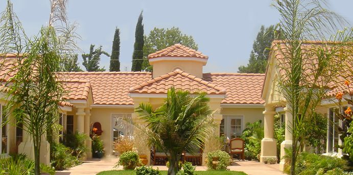 Las Casitas Assisted Living community featuring villa-style housing with tile roofs and lush plants.