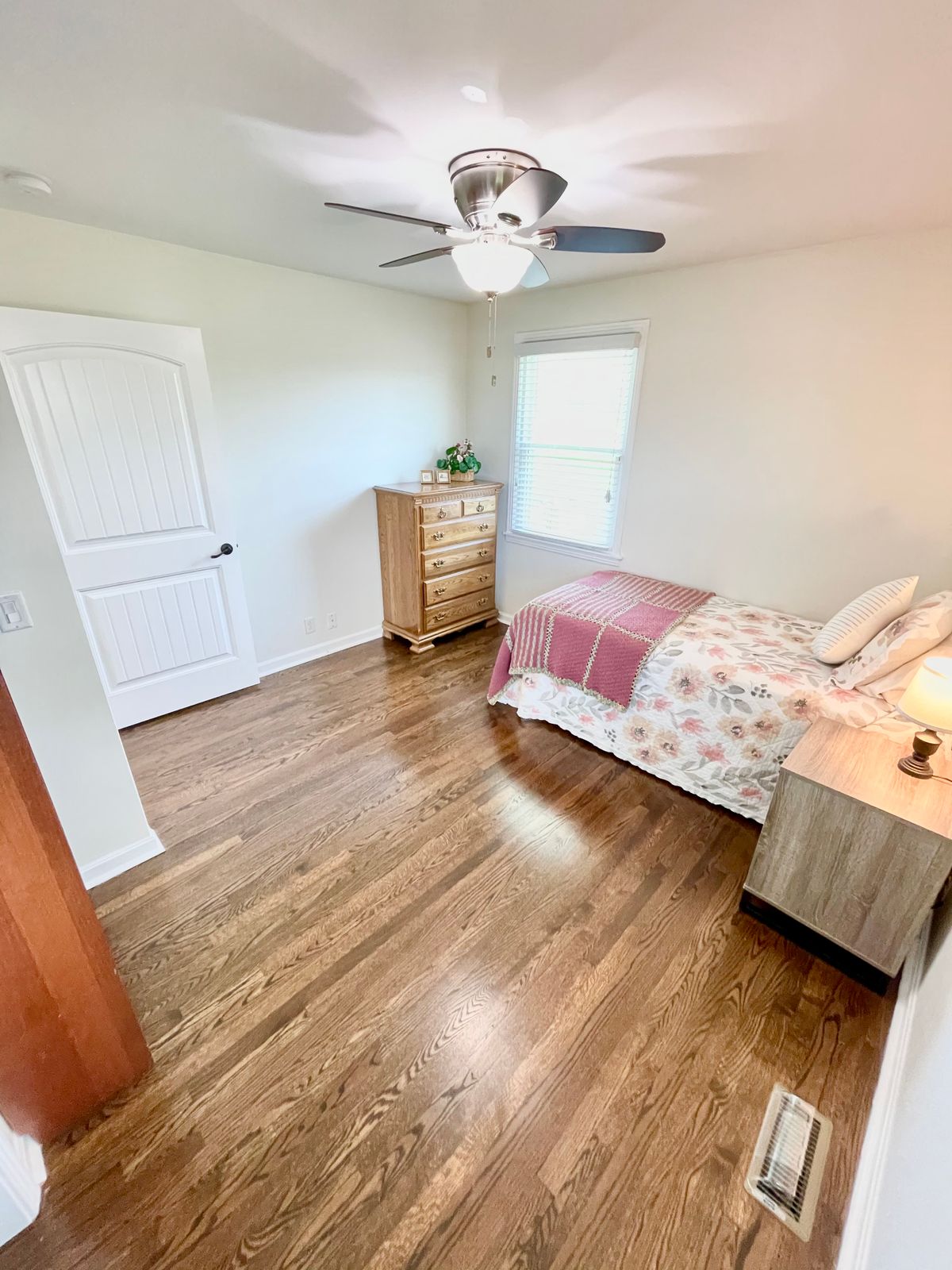 Interior view of Silver Lining Home and Care with hardwood flooring, ceiling fan, and bed.