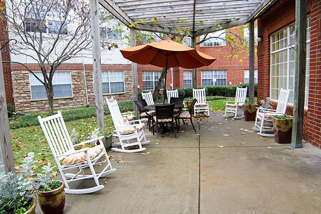 Brookdale Franklin senior living community featuring a porch with rocking chairs, a garden, and outdoor dining.