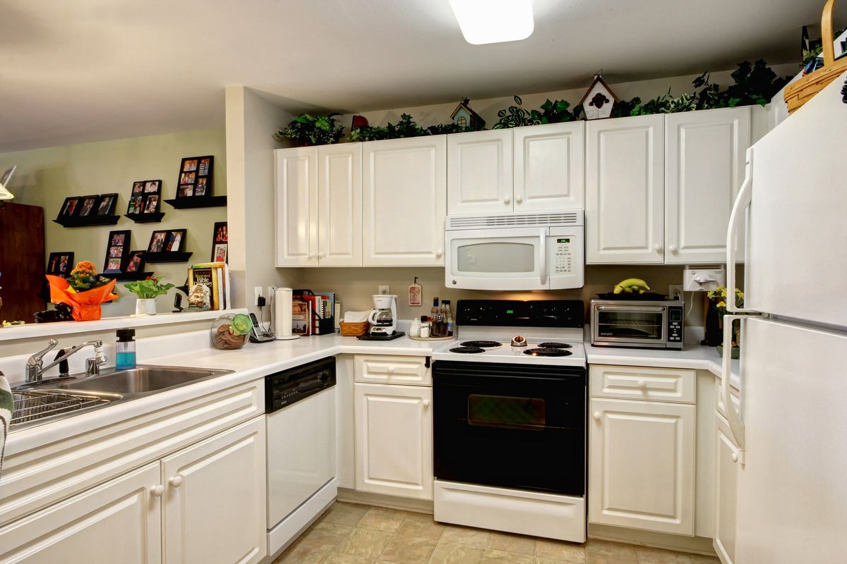 Senior resident in a well-equipped kitchen at Madison Village with modern appliances and plants.