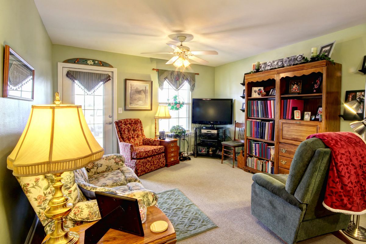 Senior living room in Madison Village with modern decor, electronics, and a resident.