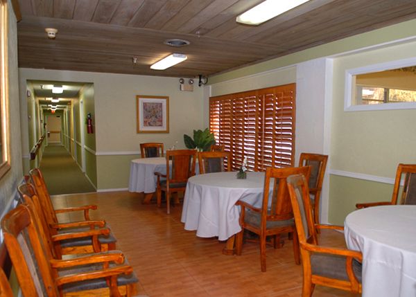 Interior view of Manatee River Assisted Living, showcasing hardwood flooring, dining furniture, and architecture.