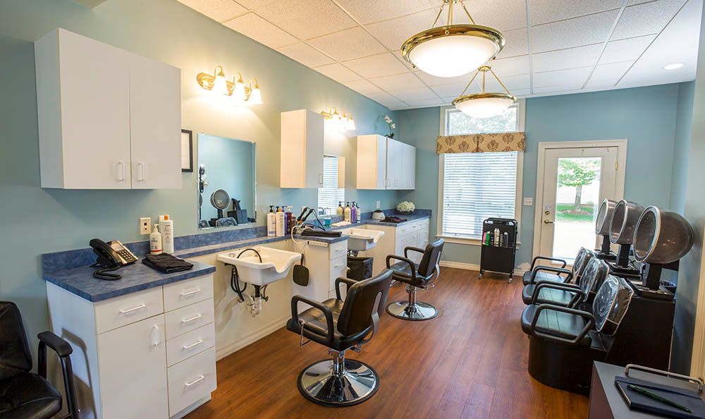 Indoor view of Benchmark Senior Living At Robbins Brook featuring a beauty salon, barbershop, chandelier, lamp, and sink.