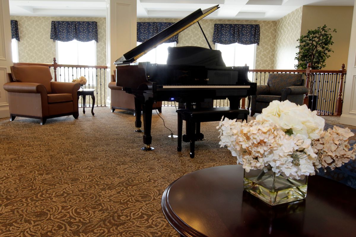 Senior living community room in Florence with grand piano, flower arrangements, and wooden furniture.
