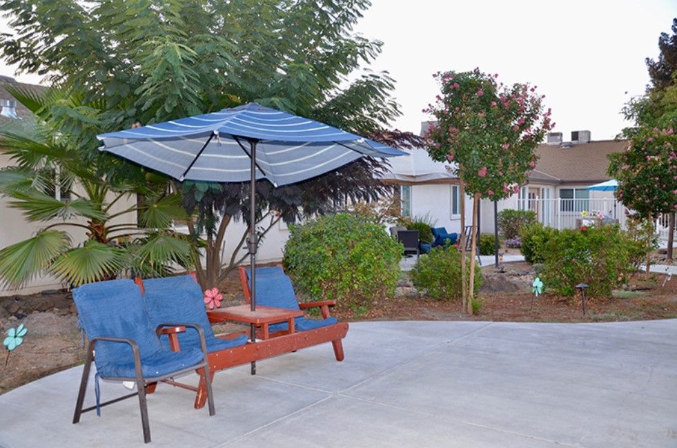 Senior living community Hospitality House featuring a patio, backyard with lush greenery, and cozy interior design.