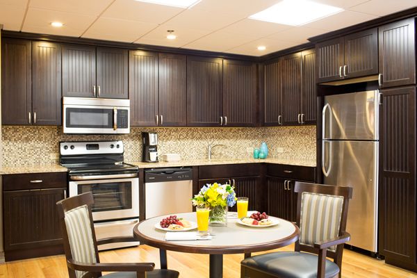 Interior design of a kitchen in Indoors Senior Living Community featuring wooden furniture and appliances.