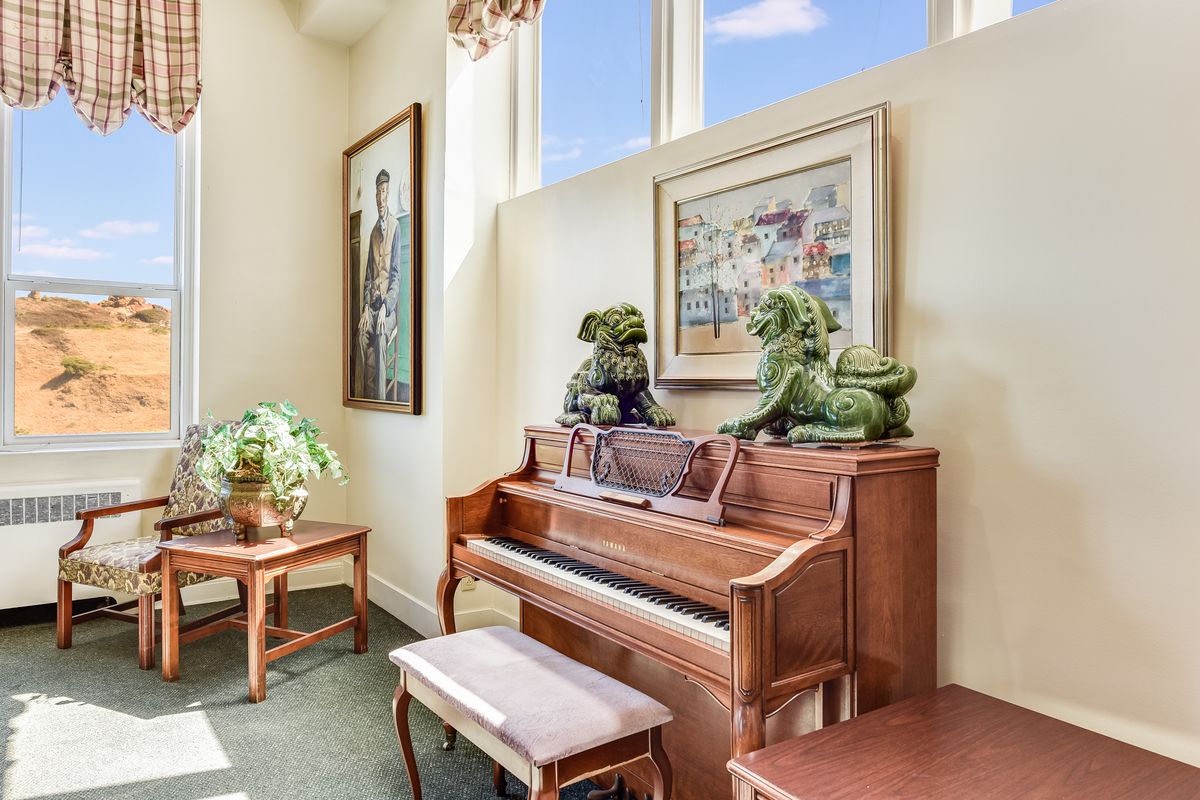 Interior view of Buena Vista Manor House featuring grand piano, wooden furniture, and art.