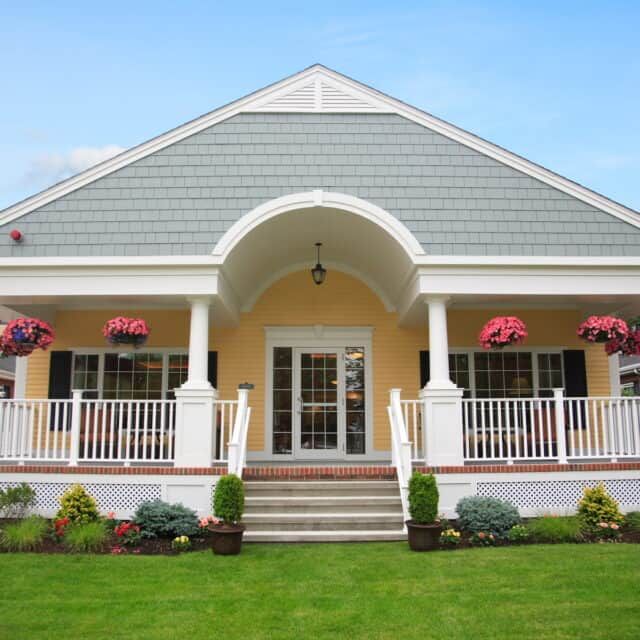Compass On The Bay senior living community featuring a portico, lamp, and lush plants.