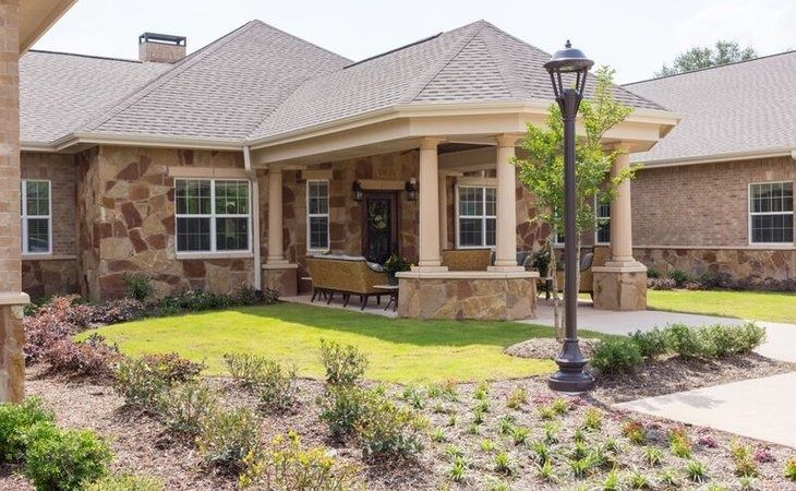 Senior living community, Bader House of Georgetown, featuring a portico, grassy lawns, and outdoor furniture.