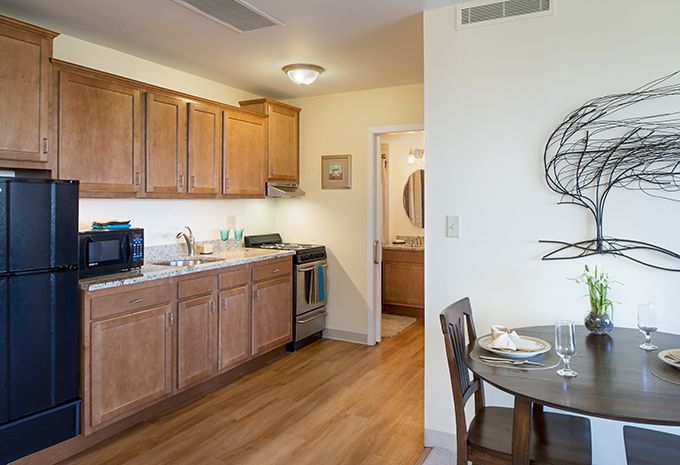 Interior view of AVIVA Country Club Heights senior living community featuring a well-furnished dining room and kitchen.