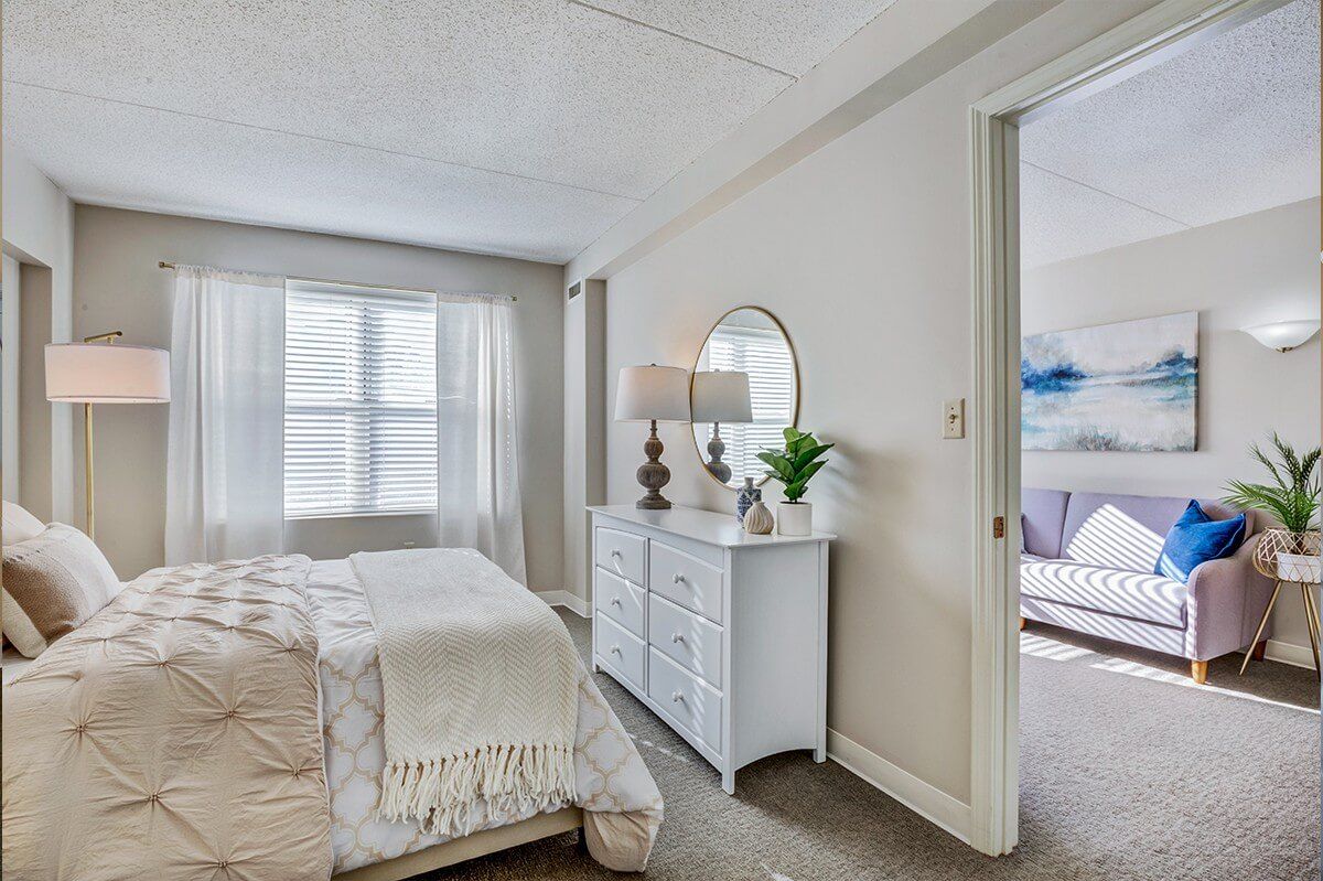 Interior design of a bedroom with furniture and bay window at Chestnut Park Senior Living.