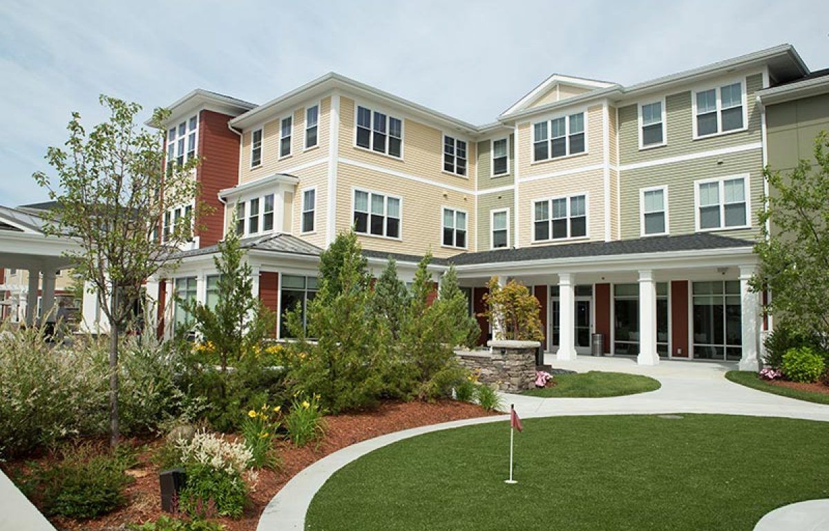 Seniors enjoying urban life at the Wingate Residences in Needham, surrounded by lush lawns and modern condos.