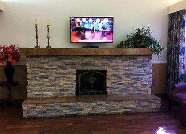 Indoor view of Karlton Residential Care Center with modern electronics, furniture, and cozy fireplace.