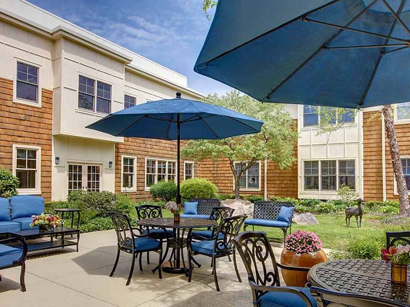 Architectural view of Atria Darien senior living community with outdoor patio and wildlife.