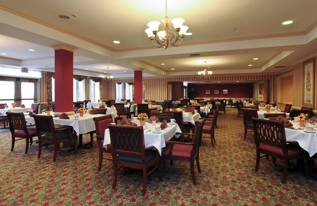 Seniors enjoying a banquet at Storypoint Libertyville's dining hall with elegant furniture and architecture.