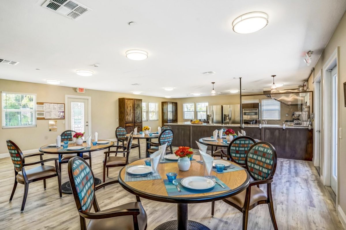 Senior living community Palm View Pleasant Living featuring a well-furnished dining room and kitchen.
