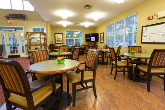 Senior living community dining room with wooden furniture and computer monitors in Elk Grove Park.