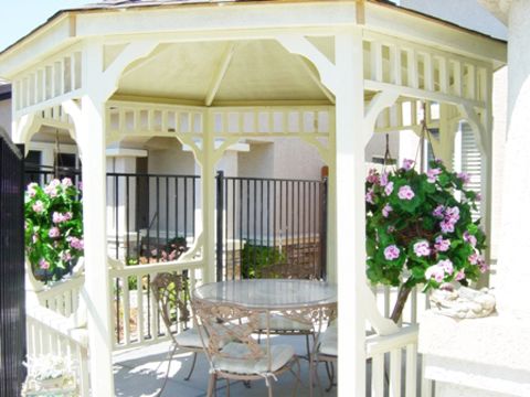 Senior living community Outdoors with architectural gazebo, dining table, chairs, plants, and flowers.