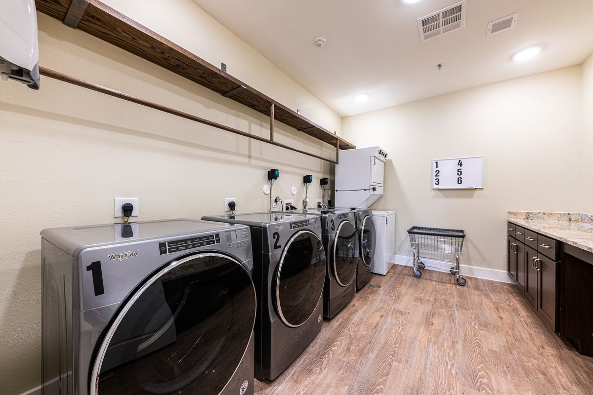 Interior view of Appliance, a senior living community, featuring laundry room with washer and hardwood floors.
