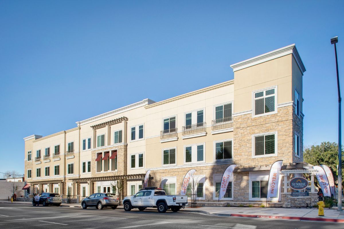 Senior living community, Oakmont of Redwood City, featuring high-rise apartments, vehicles, and residents.