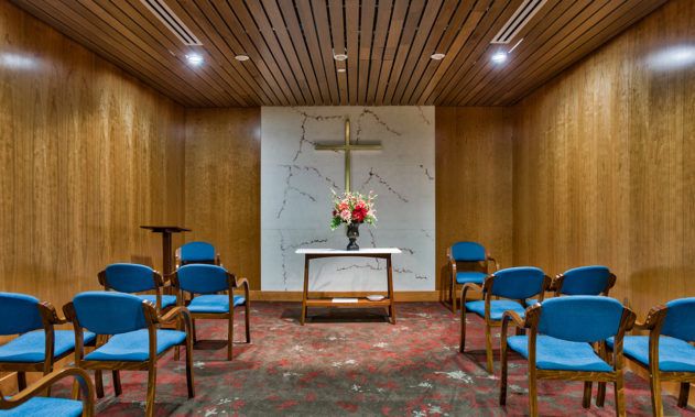 Interior view of Silvercrest at College View senior living community featuring chapel with cross and flower arrangements.
