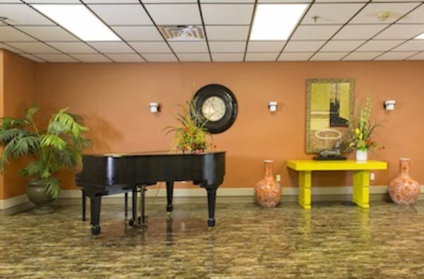 Senior living community interior with piano, plants, and elegant flooring at Stella Manor.