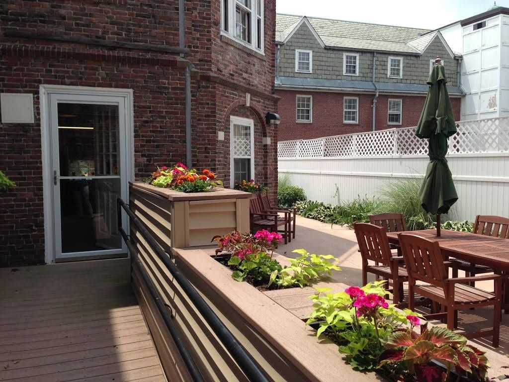 Senior living community, Landmark At Longwood, featuring a deck with potted plants and outdoor furniture.