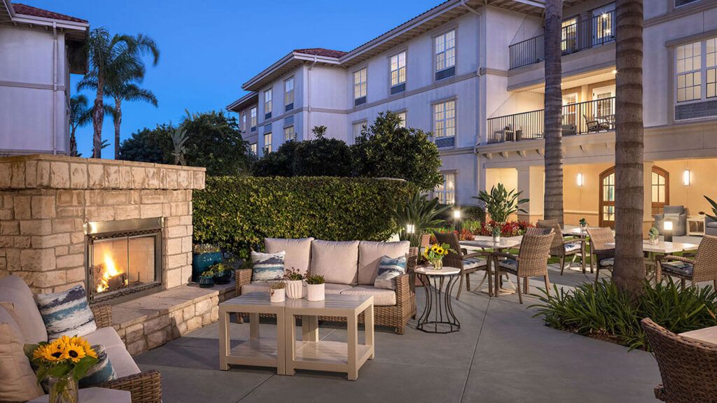 Senior living community at Belmont Village Rancho Palos Verdes featuring indoor fireplace, outdoor terrace, and dining area.