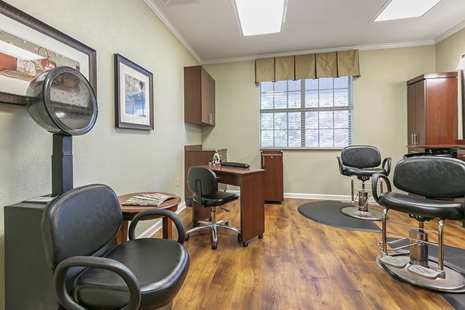 Senior resident at Brookdale Germantown using a laptop at a desk with art and salon in background.