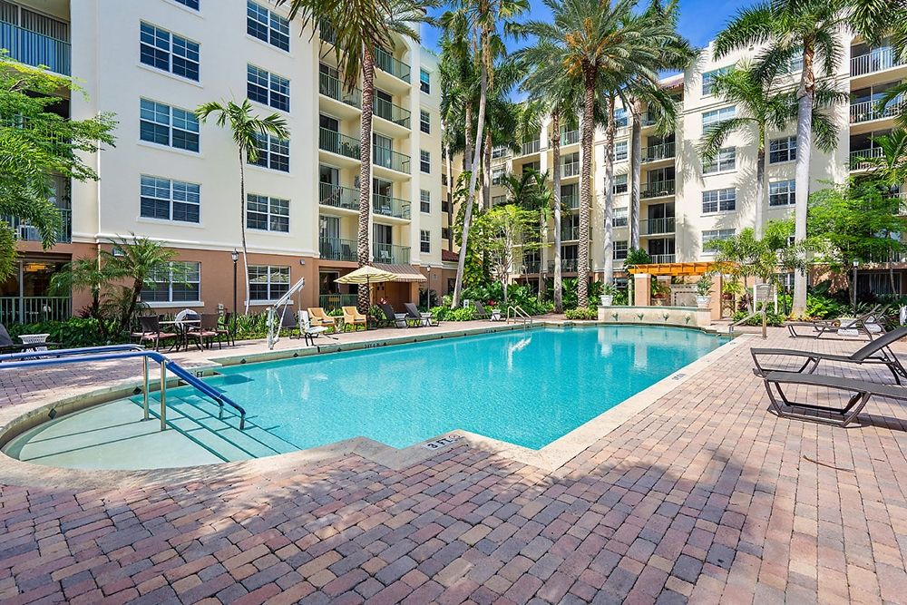 Senior living community, The Carlisle Palm Beach, featuring a pool, condos, and lush nature.