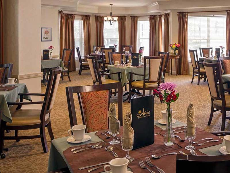 Senior living community Atria Park of Glen Ellyn featuring dining room with furniture and decor.