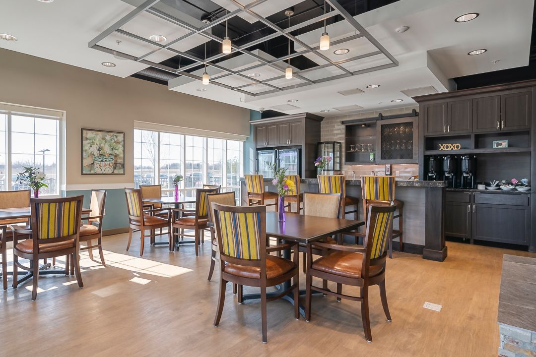 Interior view of Avalon senior living community featuring dining room, kitchen, and hardwood flooring.