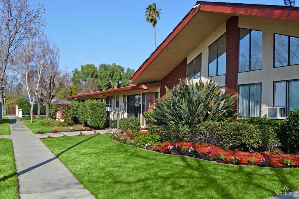Grass and plant-filled neighborhood of Lincoln Villa senior living community with walkways and trees.