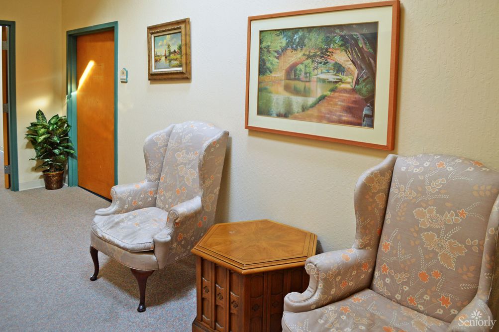 Interior view of Lincoln Villa senior living room with elegant furniture, wood flooring, and flowers.