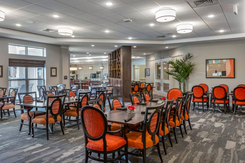Indoor cafeteria at Tiffany Springs Senior Living Community featuring dining tables, chairs, and lounge area.