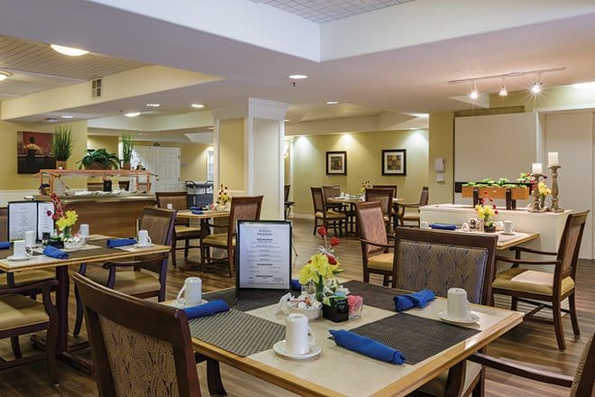 Senior residents dining in the elegant restaurant at Brookdale San Ramon with art and plants.