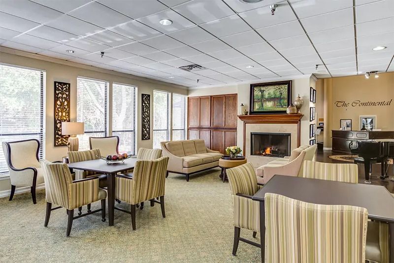 Senior residents relaxing in the Continental Retirement Community's elegant lounge with cozy fireplace.