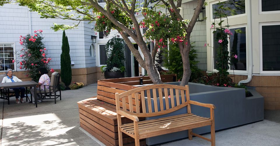 Senior living community El Cerrito Royale featuring indoor and outdoor furniture, potted plants, and architecture.