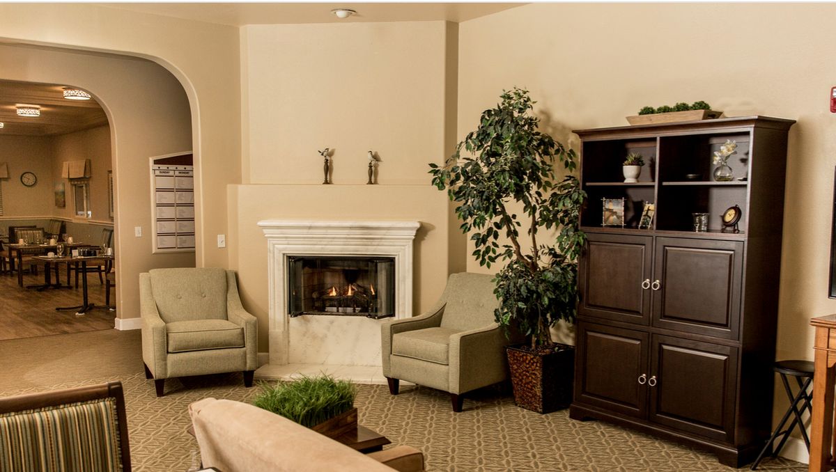 Senior living community interior featuring modern architecture, cozy living room with fireplace, and lush plants.