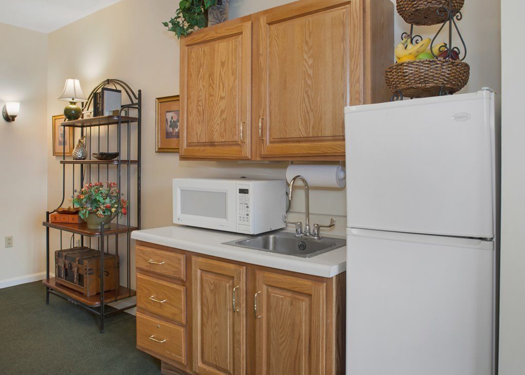 Interior view of Sunrise Assisted Living Leawood's kitchen with modern appliances and wooden furniture.