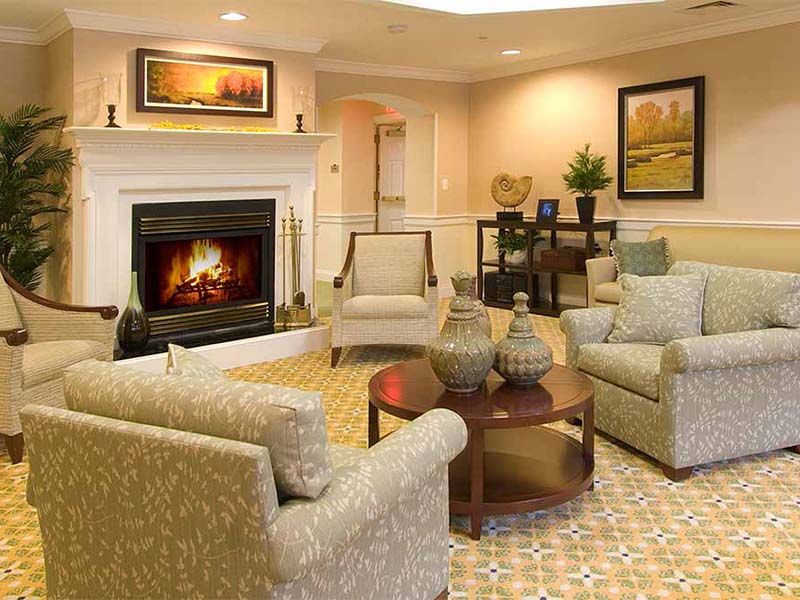 Senior living room at Atria Longmeadow Place with cozy fireplace and elegant home decor.