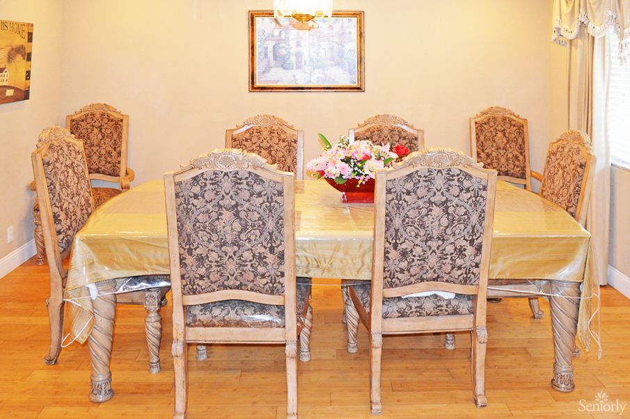 Senior living community interior featuring a dining room with wooden furniture and floral decor.