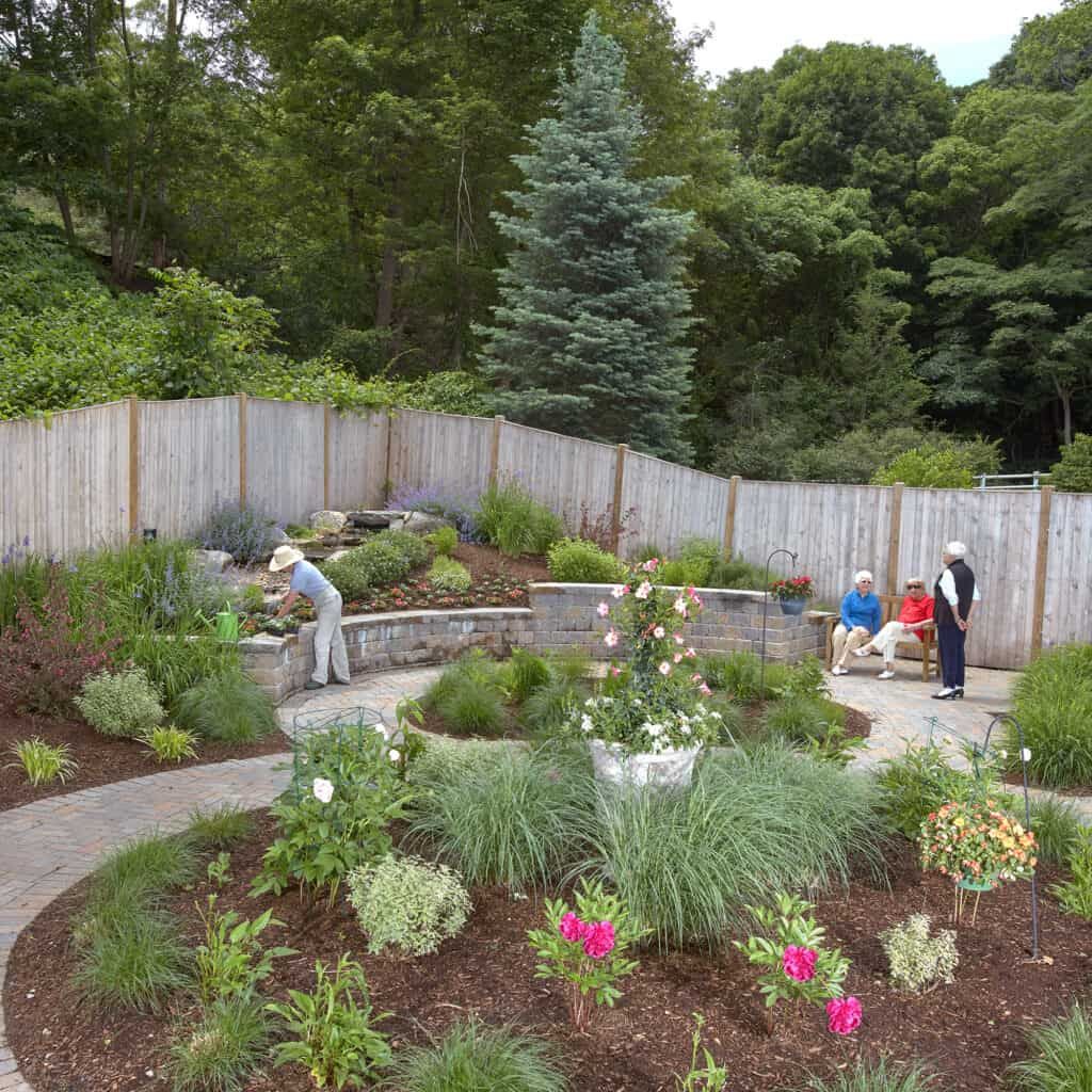 Senior gardening in the lush backyard of Goddard House, a nature-filled senior living community.