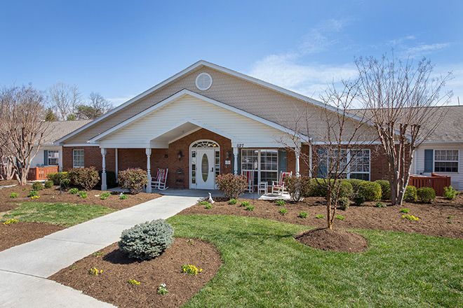 Brookdale Roanoke senior living community with lush lawn, trees, birds, and outdoor furniture.