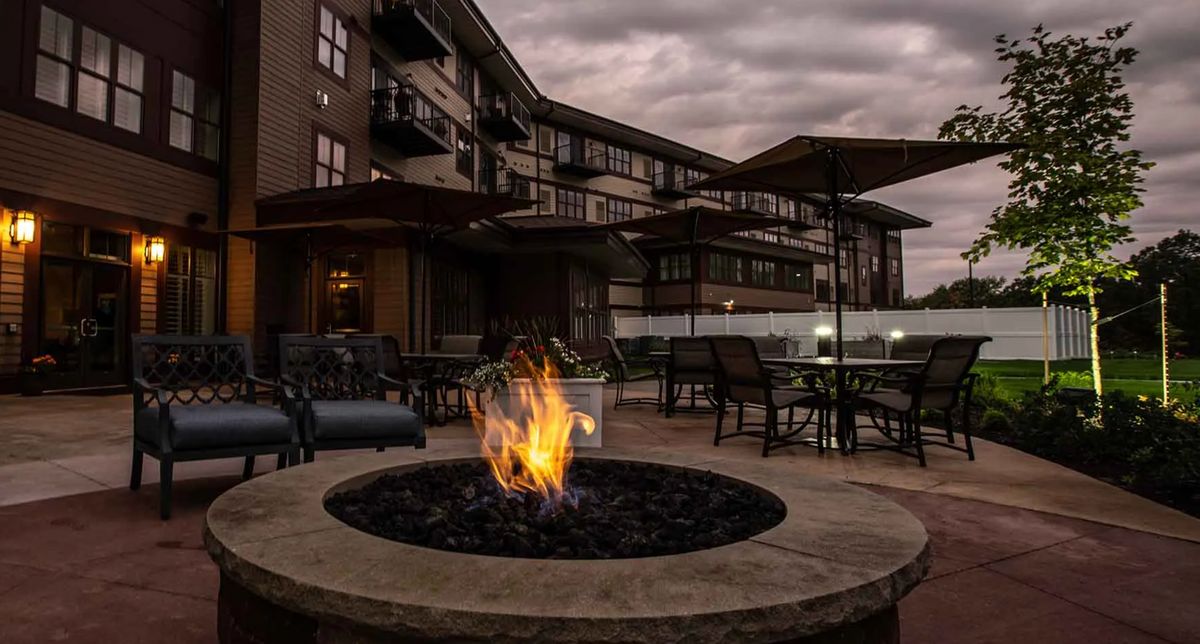 Senior living community, Grand Living at Georgetown, featuring outdoor patio, bonfire, and scenic city views.