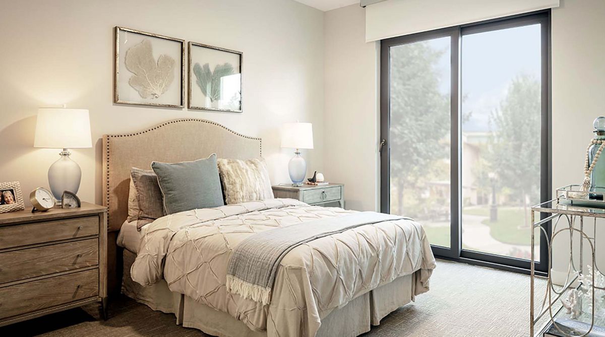 Senior resident relaxing in a well-decorated bedroom at Atria Newport Beach with elegant furniture.