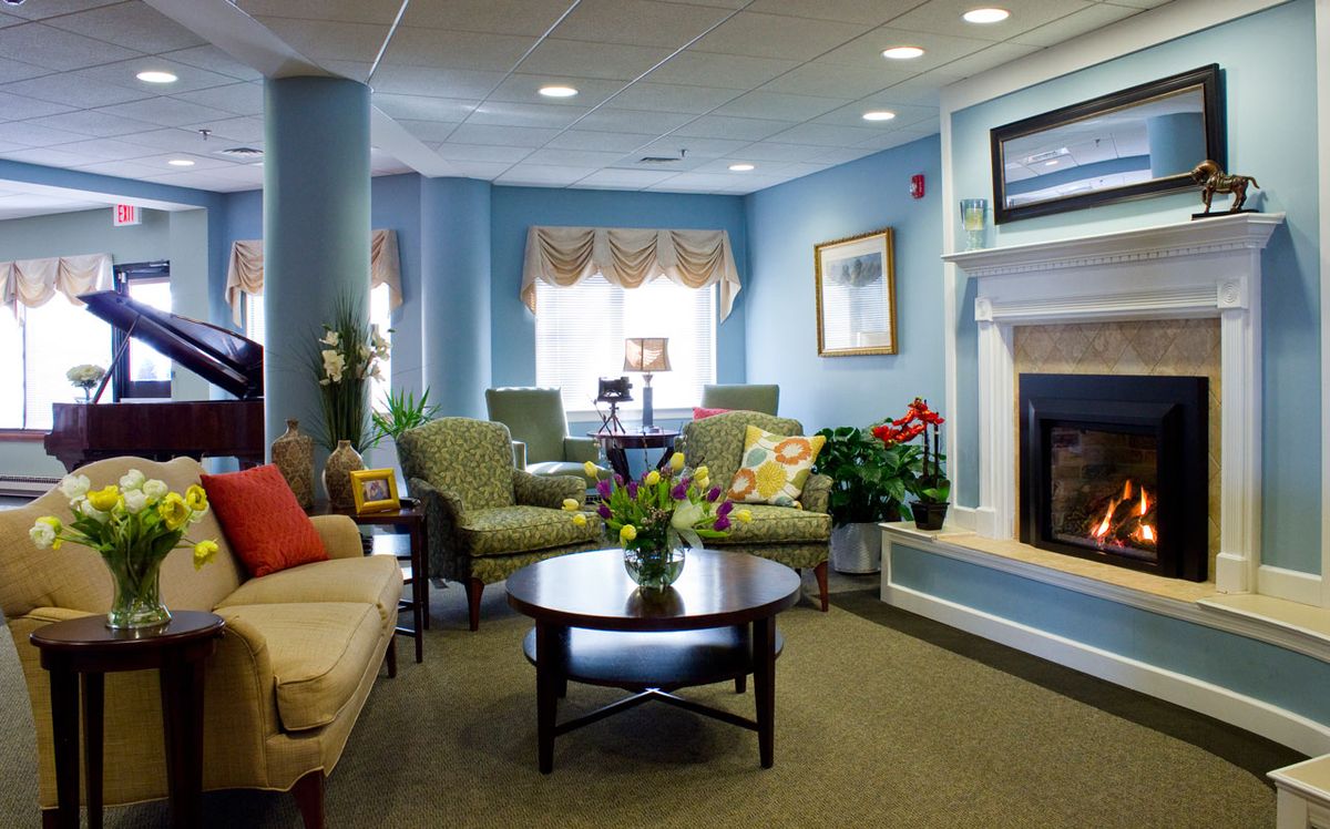 Senior living room interior at Highlands On The East Side with cozy fireplace and floral decor.